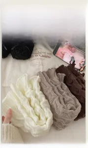 Détail macro de jambières en maille blanche, grise et marron avec bords volantés