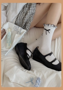 Detail of white ribbed crew socks featuring plaid ruffles and a delicate black bow