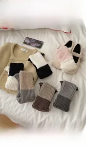 Vue détaillée de jambières en tricot bicolore avec texture côtelée sur un lit douillet