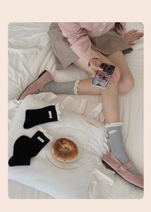 Detail of lace-trim mid-calf socks with vintage ribbed texture and woven letter label