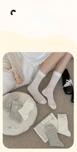 Close-up of knit crew socks with delicate bow accents and heart button patterns