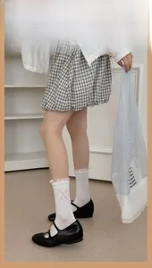 Detail of white mid-calf socks with pink bows and lace trim paired with Mary Jane shoes
