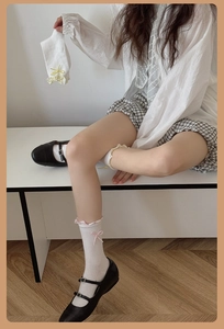 Close-up of white mid-calf socks with delicate lace trim and pink ribbon bows