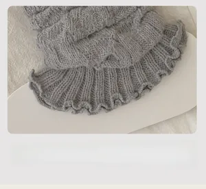 Détail de jambières grises en maille torsadée montrant la texture et le bord côtelé