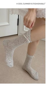 Detail of grey mesh mid-calf sock featuring bow tie, heart button and floral jacquard