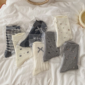 Women's crew socks with plaid patterns, floral prints, and bow accents in neutral grey tones