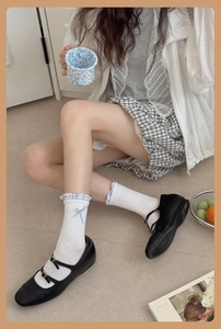 Close-up of white ruffle socks with blue bows paired with black Mary Jane shoes