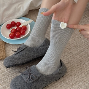 Grey ribbed knit crew socks with white heart detail paired with grey bow slippers