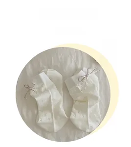 Detail of white cotton baby socks with delicate hollow patterns and polka dot bows