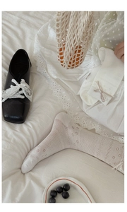 Detail of cream calf socks with mesh patterns, satin bows, and vintage ruffled edges