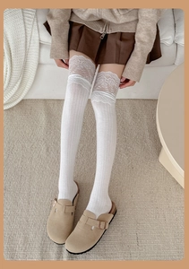 Detail of white over-the-knee socks featuring wide lace cuffs and vertical striped texture