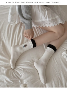 Détail de la broderie d'ours mignon sur des chaussettes japonaises en coton crème