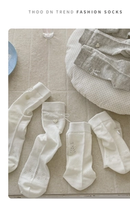 Detail of sweet ballet-style socks with heart buttons, bows, and hollow dot jacquard texture