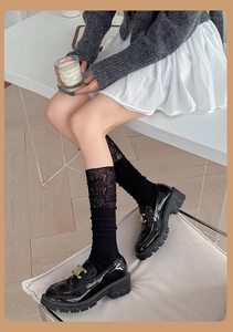 Close-up of black lace patchwork socks paired with patent leather loafers and metal buckle