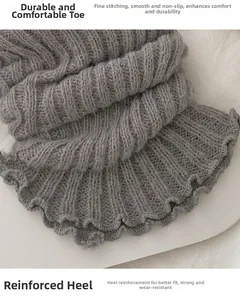 Détail macro de jambières en tricot gris montrant le talon renforcé et les coutures fines
