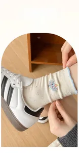 Detail of embroidered elephant on beige cotton socks with blue wavy ruffled cuffs