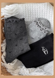 Dettaglio di calze in cotone grigio e nero con fiocchi ricamati e scritta Sweet Love