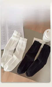 Close-up of white and black ribbed crew socks with ruffled edges on a table