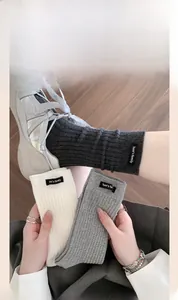 Detail of ribbed knit socks in grey and cream colors with Tom's family logo patches