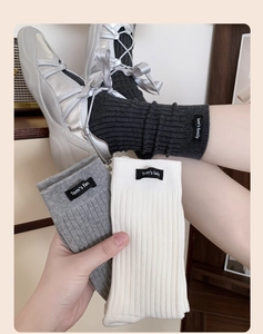 Detailed texture of grey ribbed mid-calf knit socks featuring a Tom's family cloth tag