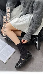 Detail of black ribbed mid-calf socks paired with glossy patent leather Mary Jane shoes