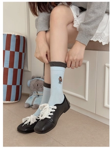 Gros plan de chaussettes en coton bleu clair avec broderie ours et bordure grise