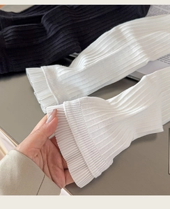 Detail of ruffled cuffs on vertical ribbed knit arm warmers in black and white