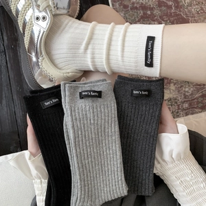 Minimalist ribbed mid-calf socks in white, black and grey with woven letter tags