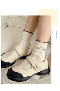 Close-up of retro Mary Jane shoes with metal buckle and embroidered cotton socks
