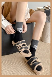 Detailed view of koala embroidery on grey patchwork socks with faux fur slippers