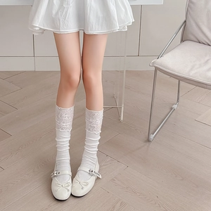 White ballet style lace trim mid-calf socks paired with bow Mary Jane shoes on a model