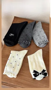 Dettaglio di cinque paia di calze di cotone grigie e beige con bordo in pizzo e fiocchi