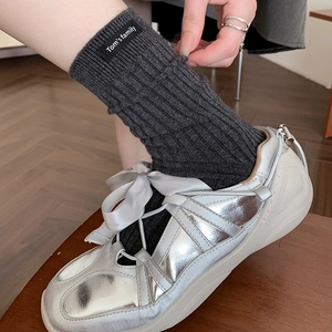 Fashionable dark grey ribbed crew socks with letter label paired with silver sneakers