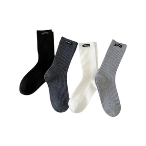 Set of four ribbed crew socks in black, dark grey, white, and light grey with brand tags