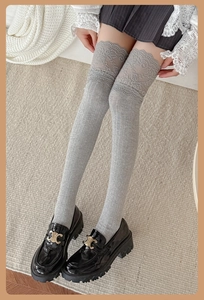 Detail of grey over-the-knee socks featuring delicate lace trim and ribbed knit texture
