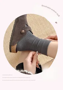 Close-up of grey ribbed cotton socks paired with brown suede buckle clogs shoes