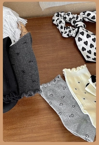 Primo piano di calzini in cotone con motivi a fiocco, cuori e pois in grigio e beige