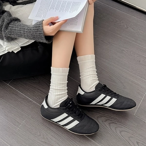 Classic black casual sneakers with white stripes paired with ribbed frilly socks