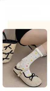 Detail von weißen Netzsocken mit bunten Punkten und Rüschen-Spitzenbesatz für Damen