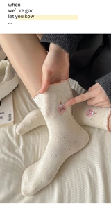 Detail of white knit socks with pink cat embroidery and decorative ruffled edges