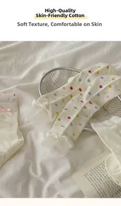 Nahaufnahme weißer Baumwollsocken mit bunten Punkten und Rüschen aus Spitze