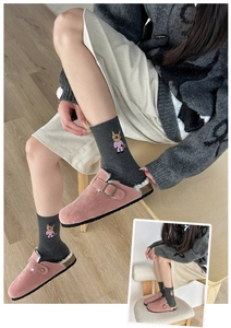 Close-up of pink suede faux fur clogs paired with grey cartoon rabbit knit socks