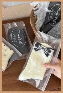 Dettaglio calzini in cotone grigio e beige con fiocco in confezione smerigliata con zip