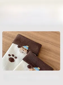 Close-up of elastic cotton cuff with cartoon dog and paw patterns on brown mid-tube socks