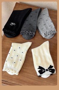 Dettaglio di cinque paia di calzini in cotone grigio e beige con fiocco e pizzo