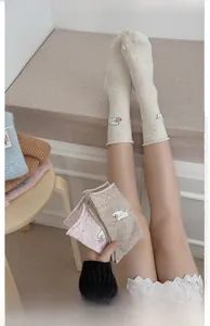 Detailed embroidery of a white poodle on marled knit crew socks with colorful specks