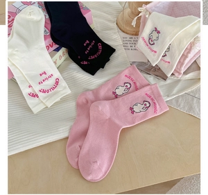 Detail of pink and white cotton socks featuring cute cartoon duck embroidery and text