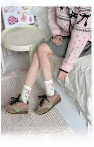 Detail of white crew socks with cartoon duck embroidery and pink sporty sneakers
