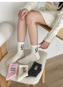 Detail of embroidered cartoon cat and rabbit patterns on colorful cotton blend socks
