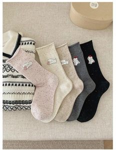 Detailed view of dog embroidery on knit crew socks with rolled cuffs in five colors